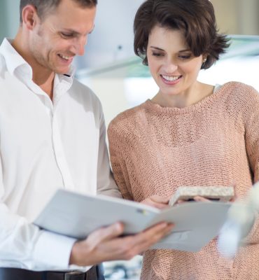 Salesman and female customer looking at brochure in kitchen showroom